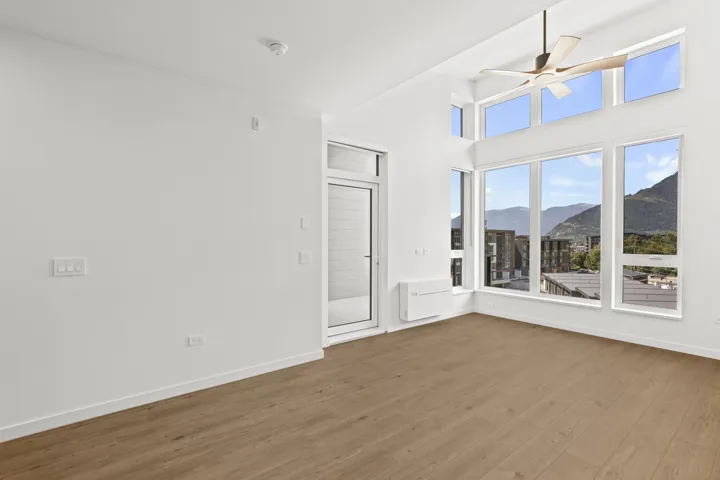 Unfurnished room featuring a mountain view, wood finished floors, a ceiling fan, and a high ceiling