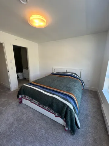 Carpeted bedroom with connected bathroom and baseboard heating