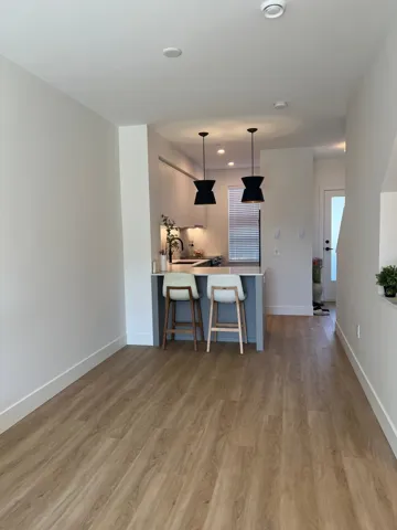 Kitchen with light countertops, a breakfast bar area, hanging light fixtures, a peninsula, and light wood-style floors