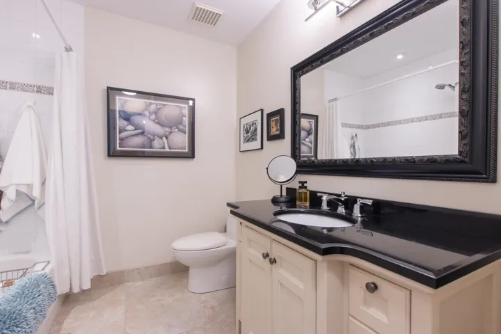 Bathroom with toilet, vanity, baseboards, and tiled shower / bath