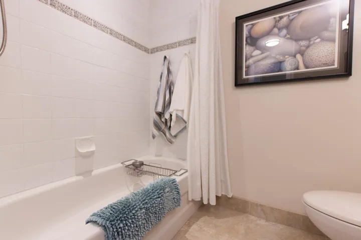 Full bathroom with toilet, shower / bathtub combination with curtain, and baseboards
