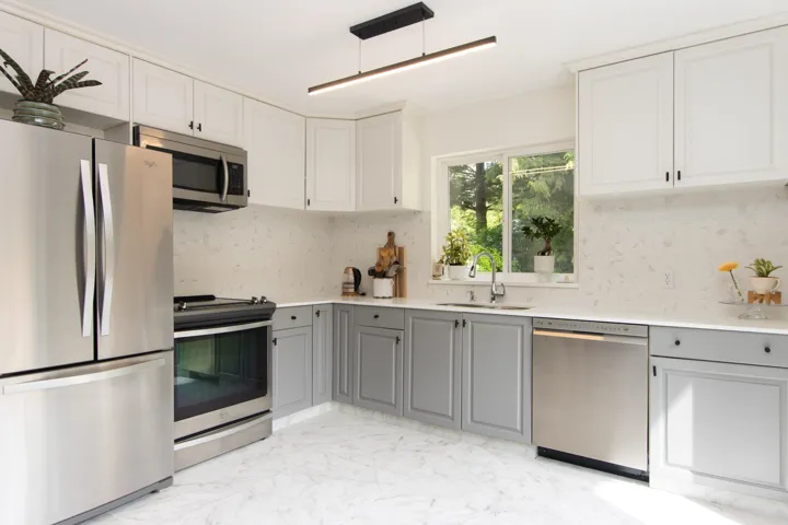 Kitchen featuring appliances with stainless steel finishes, gray cabinets, a sink, light marble finish flooring, and light countertops
