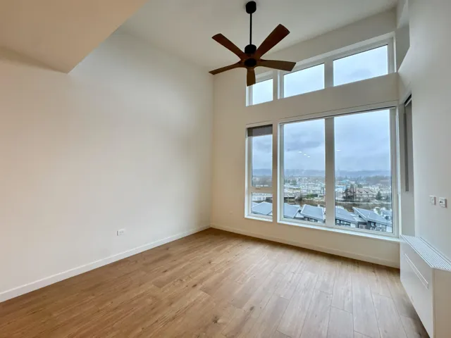 Spare room with light wood-style floors, ceiling fan, radiator, a city view, and a high ceiling