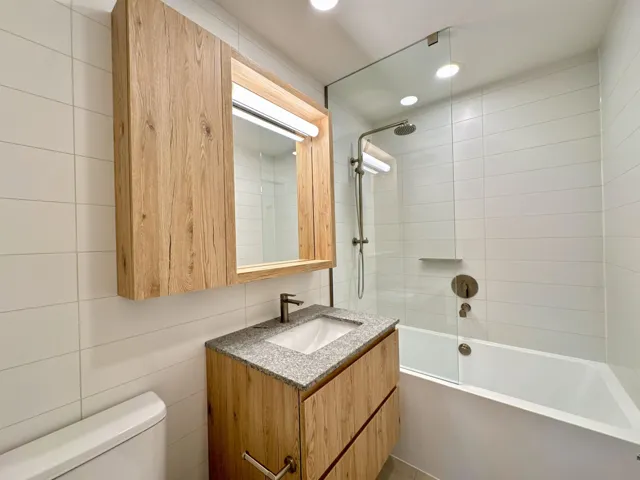 Full bath with vanity, shower / bath combination, recessed lighting, and tile walls