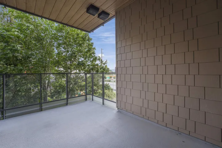 Private balcony featuring a textured concrete surface, glass and metal railings, and a wood-finish soffit with dual integrated lighting fixtures