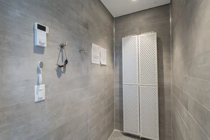 Tiled room featuring light gray horizontal tiles, recessed ceiling lighting, and a built-in four-panel perforated storage unit