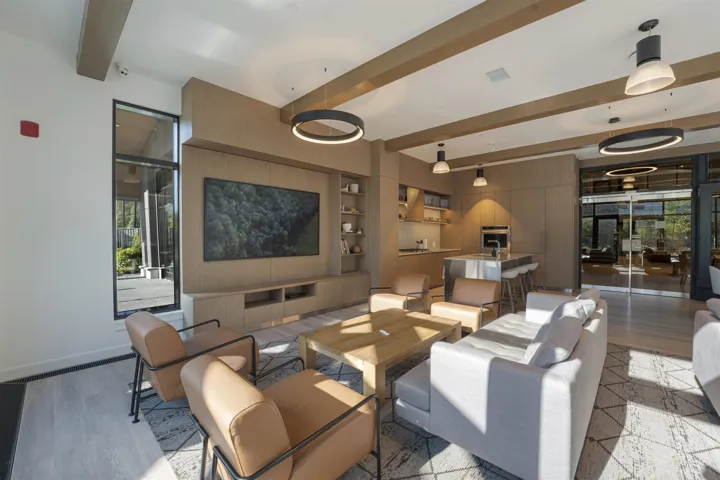 Open-concept common area featuring wood-finish flooring, exposed ceiling beams, and integrated wall-mounted media center