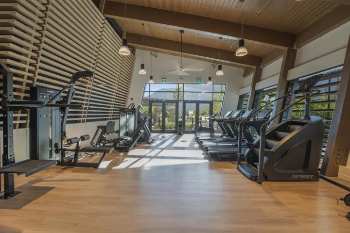 Fitness center featuring wood-finish flooring, exposed beam ceilings, and a slatted accent wall