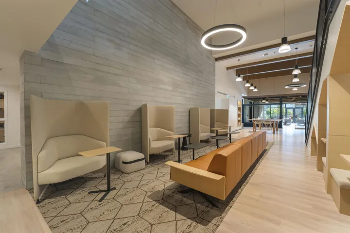 Open-concept common area featuring a textured accent wall, light wood-finish flooring, and suspended circular lighting fixtures