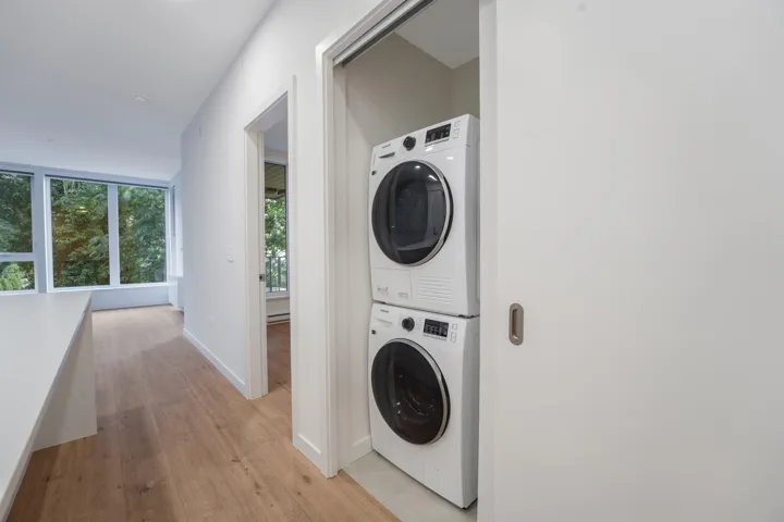 Integrated laundry closet with stacked washer and dryer, featuring a space-saving pocket door