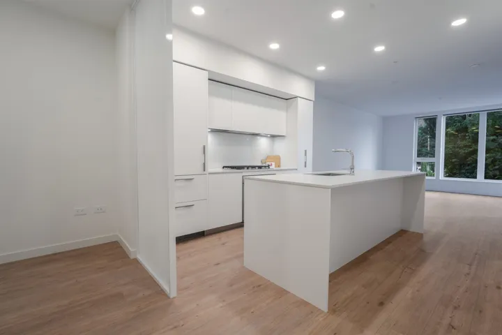 Modern kitchen featuring white flat-panel cabinetry, a stainless steel gas cooktop, and a white subway tile backsplash