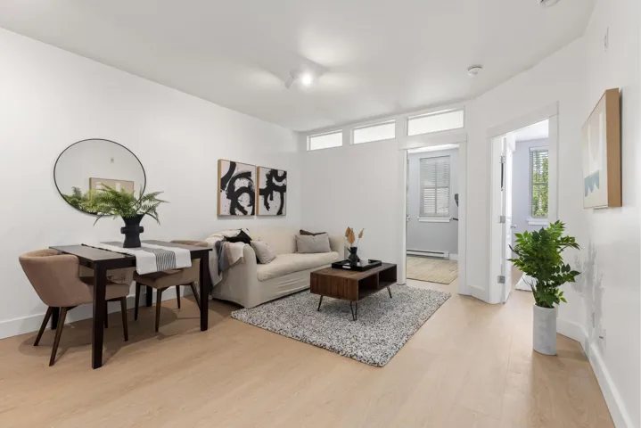 Bright open-concept living area featuring light wood-finish flooring and white walls