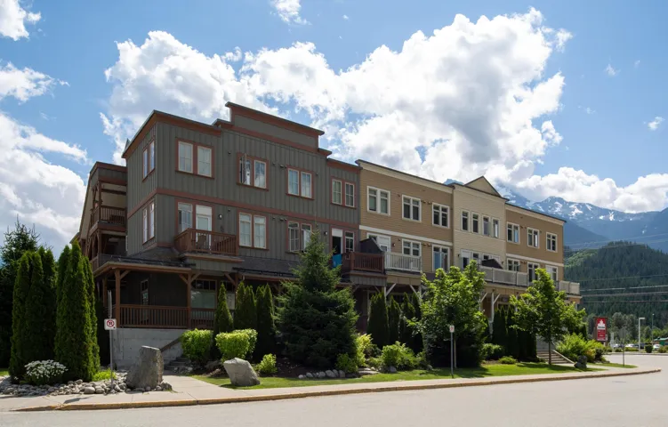 Multi-level townhome featuring a neutral-toned facade, multiple balconies, and a covered porch