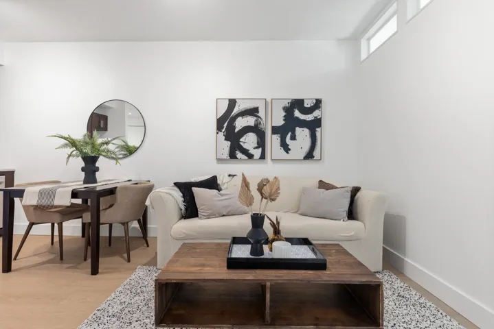 Open-concept living space featuring light wood-finish flooring, white walls, and high transom windows
