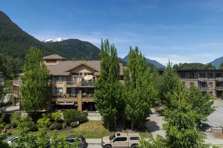 Multi-story building featuring multiple private balconies, a pitched shingle roof, and a wood-tone exterior