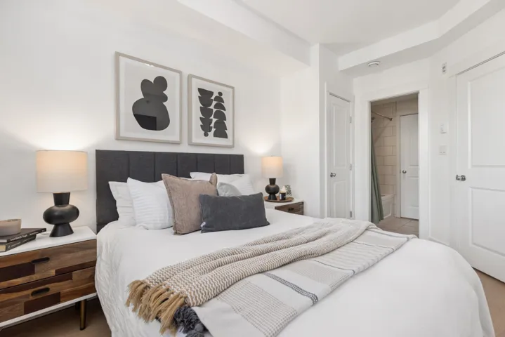 Bedroom featuring a dark upholstered headboard, white walls, and light-colored flooring