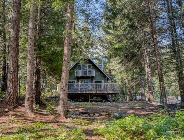Rear view of house featuring a wooded view and a deck