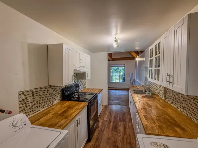 Kitchen featuring wooden counters, tasteful backsplash, and black electric range oven