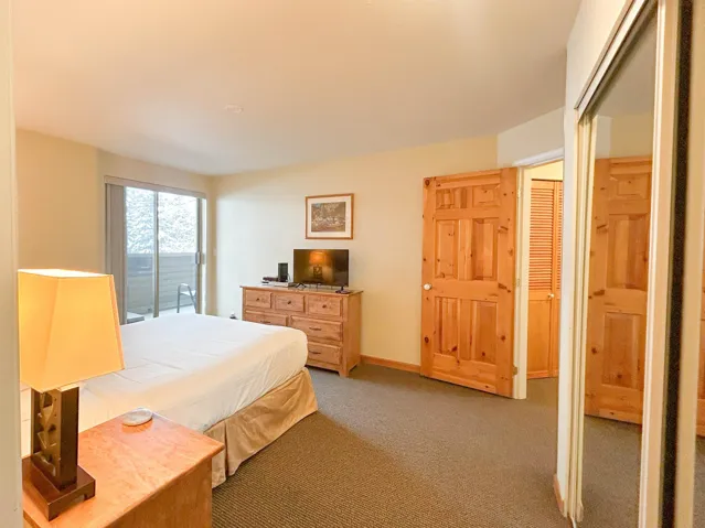 Bedroom with baseboards, access to outside, and light colored carpet