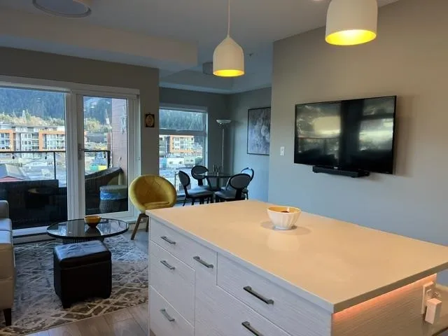 Modern kitchen island with under-cabinet lighting, light-toned countertop, and light wood-finish cabinetry