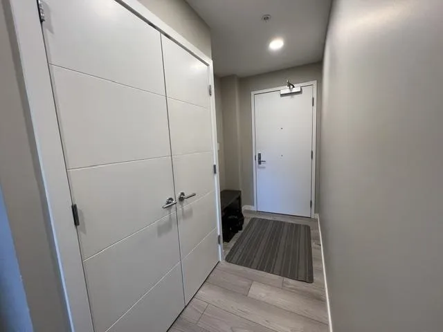 Entryway featuring wood-finish flooring, recessed lighting, and a paneled double-door closet with chrome hardware