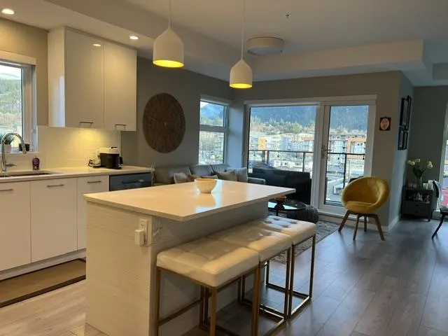 Contemporary kitchen with an island breakfast bar, sleek white cabinetry, undermount sink, and light wood-finish flooring