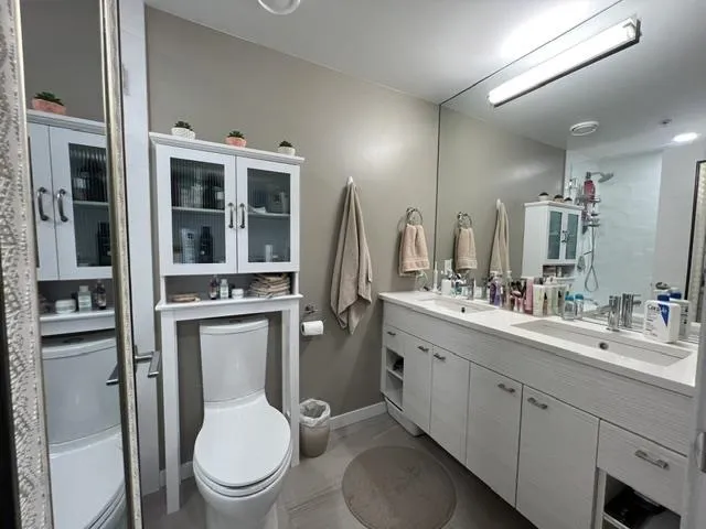 Bathroom featuring a dual vanity with undermount sinks, white cabinetry, and a full-width mirror