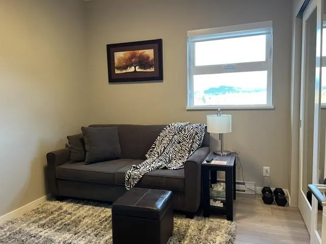 Light-filled room featuring a broad window, light wood-finish flooring, and a sliding mirrored closet door