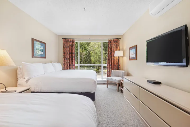 Bedroom with a wall mounted air conditioner, carpet flooring, and a textured ceiling