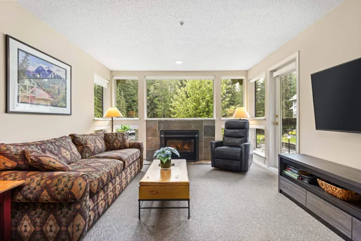 Carpeted living area with plenty of natural light, a textured ceiling, and a fireplace