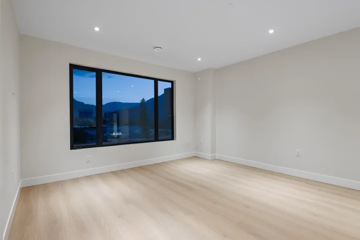 Empty room featuring light wood-style flooring, a mountain view, and recessed lighting