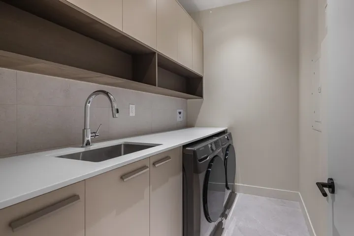 Kitchen with washer and dryer, modern cabinets, light countertops, and backsplash