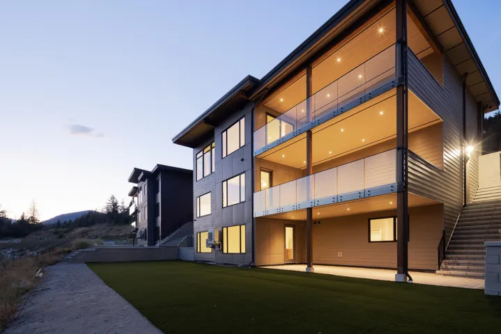 Back of house with a balcony, stairs, a patio area, and a lawn