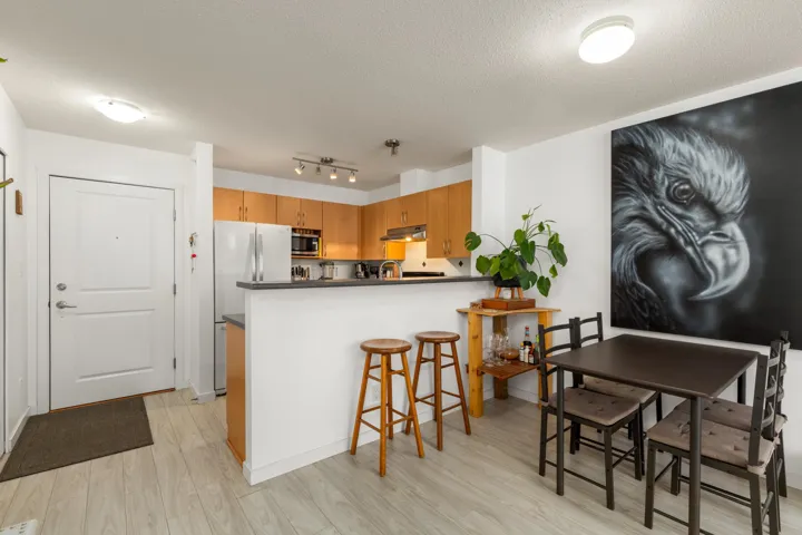 Kitchen featuring freestanding refrigerator, a breakfast bar, light wood finished floors, a peninsula, and dark countertops