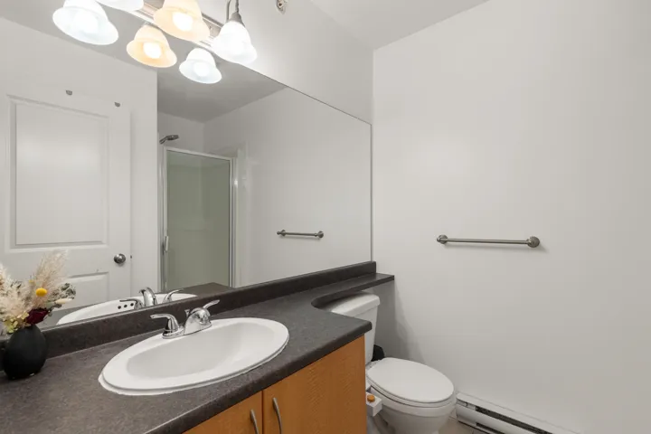 Bathroom featuring vanity, a shower stall, and baseboard heating