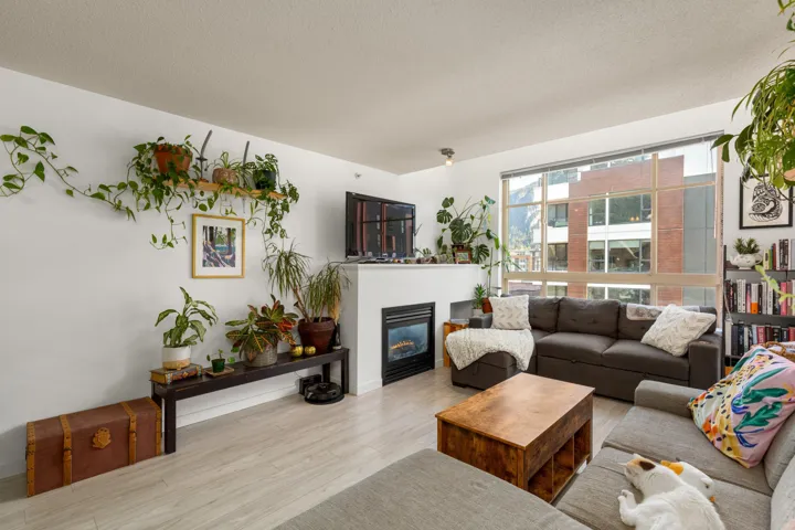 Living room featuring wood finished floors, a glass covered fireplace, and a textured ceiling