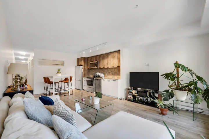Living area with light wood finished floors, a baseboard heating unit, and rail lighting