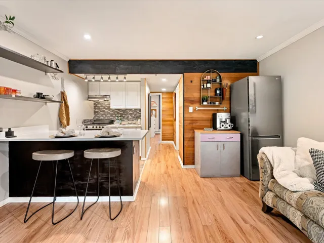 Kitchen featuring stainless steel appliances, ornamental molding, a peninsula, under cabinet range hood, and open shelves