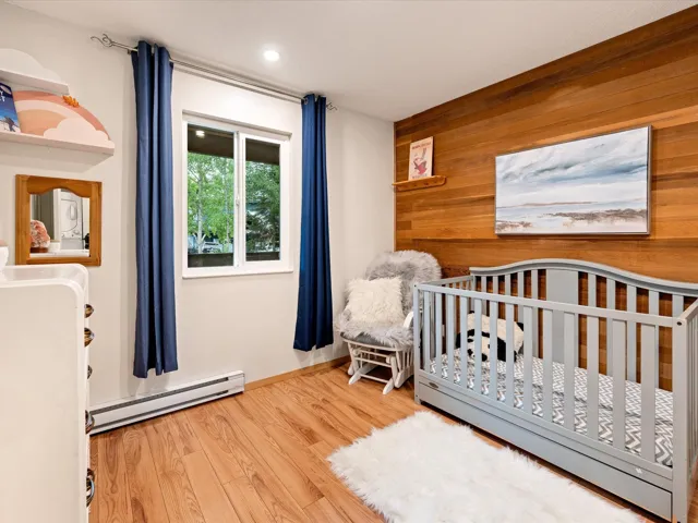Bedroom featuring baseboard heating, wood finished floors, wood walls, and recessed lighting