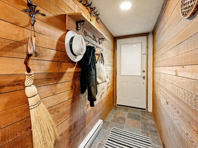 Doorway with wood walls, dark stone finish floors, and a textured ceiling