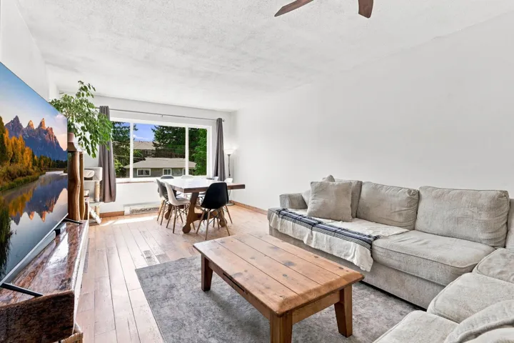 Open-concept living area featuring wood-finish flooring and white walls