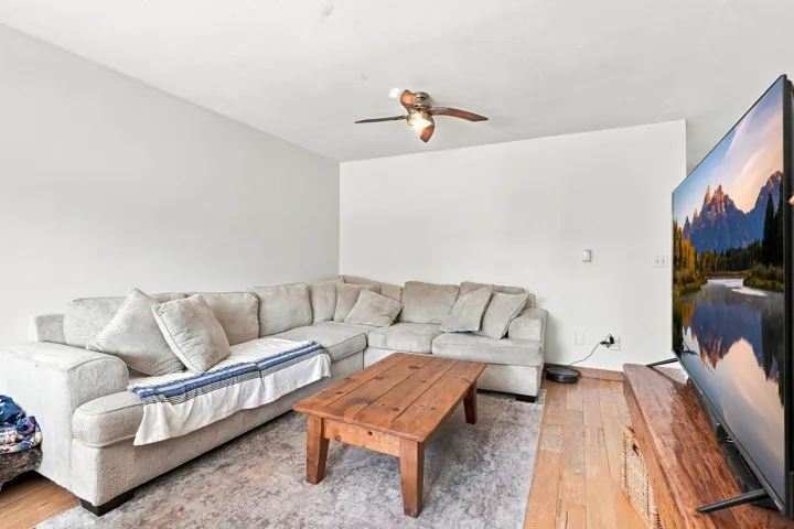 Bright interior room featuring wood-finish flooring, white painted walls, and a ceiling fan with light fixture