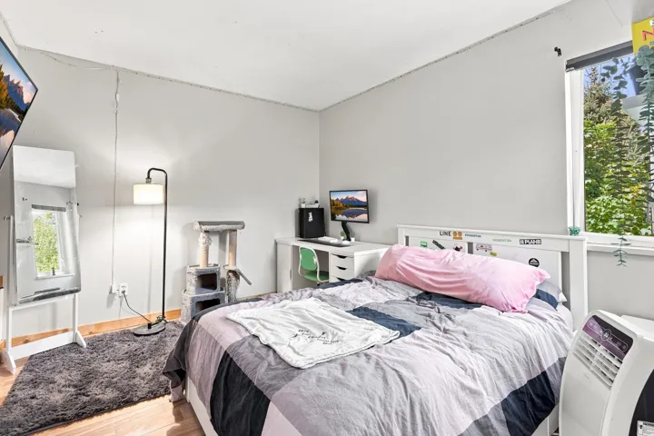 Light-filled room featuring wood-finish flooring, white walls, and a large window with exterior greenery