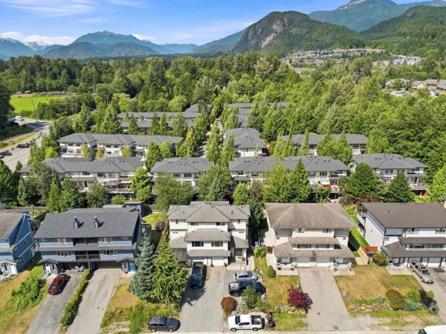 Residential development featuring multiple properties with pitched roofs and surrounding mature trees