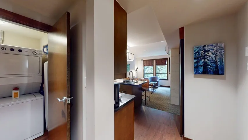 Hall with dark wood finished floors and estacked washer and dryer