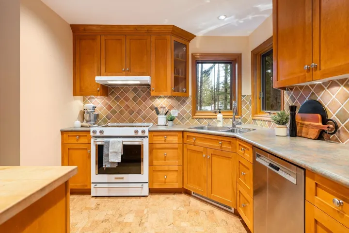 Kitchen featuring stainless steel appliances, wood finish cabinetry, glass fronted cabinets, and backsplash