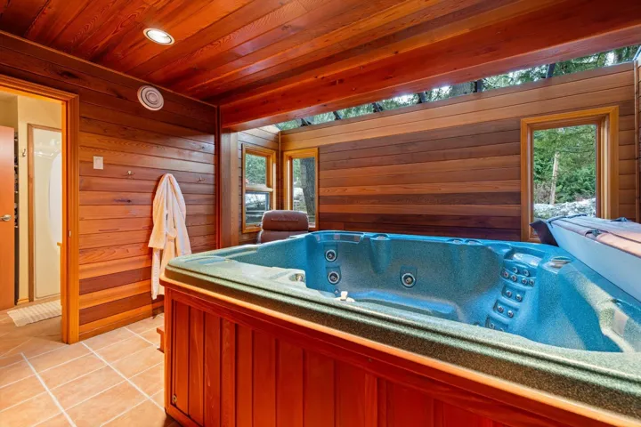 Featuring a large hot tub, wooden walls, light tile patterned floors, and wooden ceiling