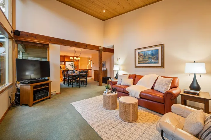 Carpeted living room featuring a high wood ceiling and a chandelier
