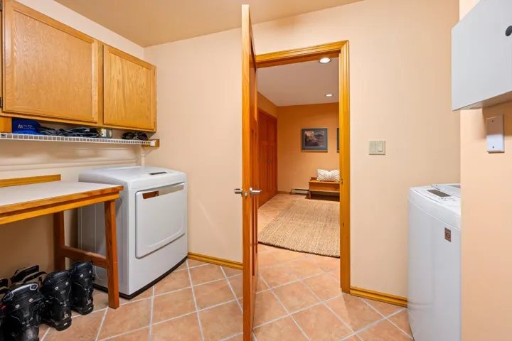 Laundry room with cabinet space, light tile patterned floors, and recessed lighting