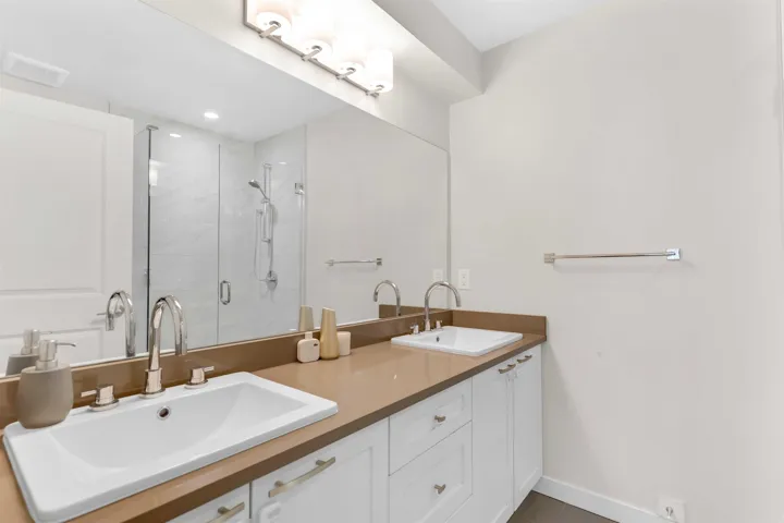 Full bath featuring a shower stall and double vanity